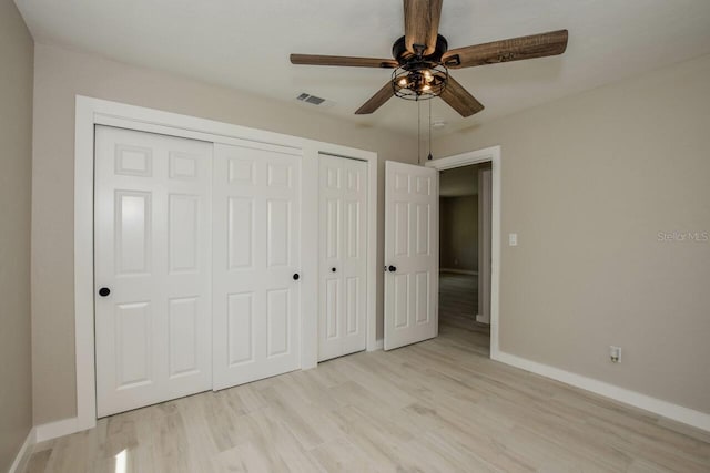 unfurnished bedroom featuring ceiling fan, light hardwood / wood-style floors, and two closets