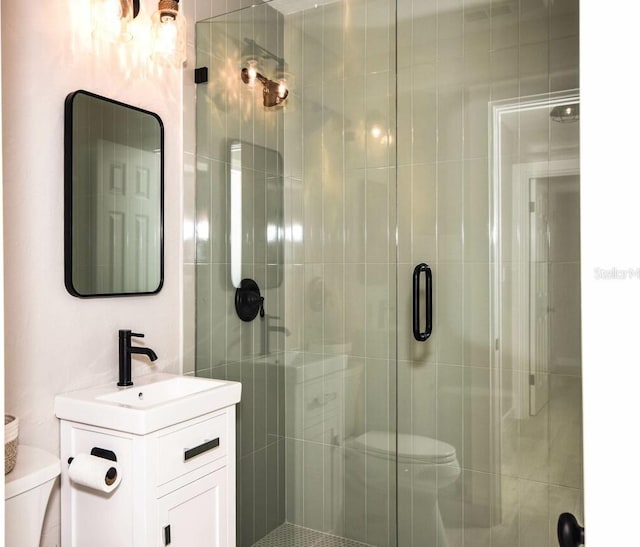 bathroom with vanity, toilet, and a shower with shower door