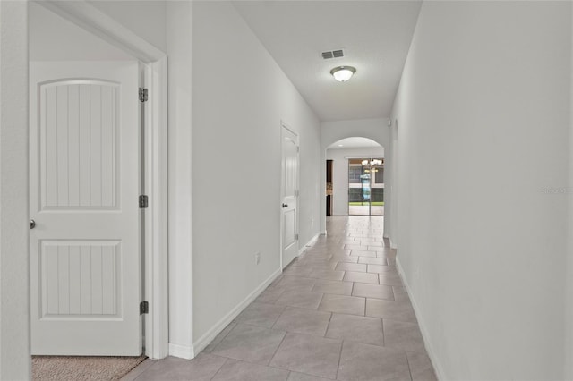 corridor with a notable chandelier and light tile patterned floors