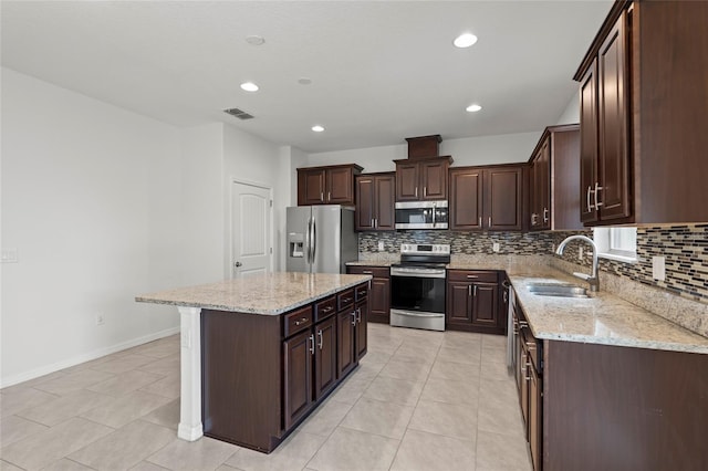 kitchen with light stone countertops, dark brown cabinetry, a center island, stainless steel appliances, and sink