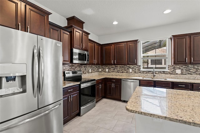 kitchen with light stone countertops, sink, stainless steel appliances, and backsplash