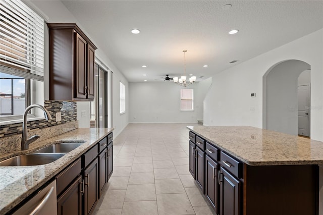 kitchen featuring a kitchen island, dark brown cabinetry, stainless steel dishwasher, and sink