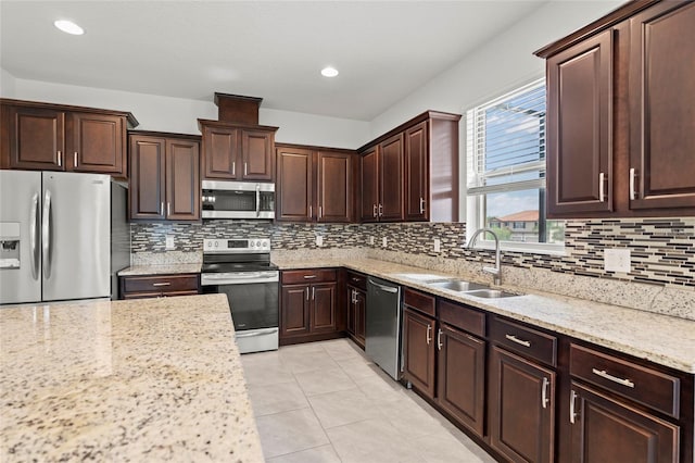 kitchen featuring light stone counters, stainless steel appliances, sink, and decorative backsplash