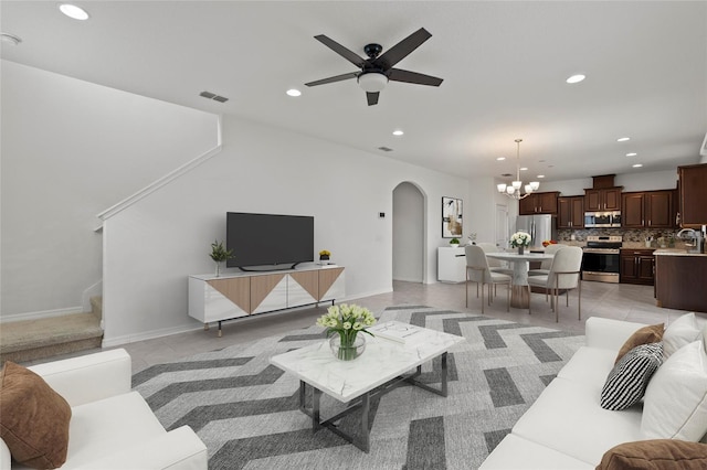 tiled living room featuring ceiling fan with notable chandelier and sink