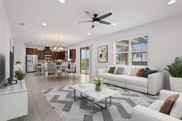 living room with ceiling fan with notable chandelier and light tile patterned floors