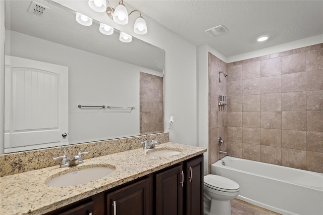 full bathroom with vanity, tiled shower / bath, a textured ceiling, and toilet