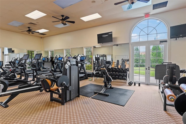 gym with a towering ceiling, french doors, light colored carpet, and ceiling fan