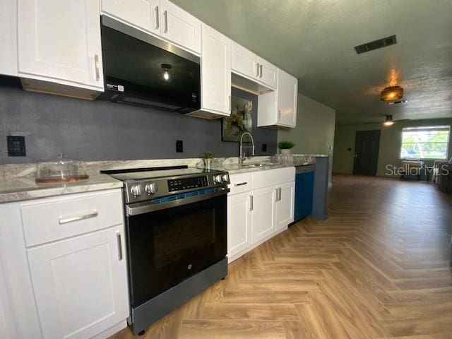 kitchen featuring black dishwasher, electric range oven, sink, white cabinetry, and light parquet flooring