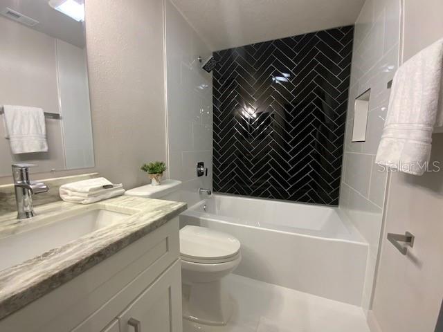 full bathroom featuring tiled shower / bath, toilet, and vanity