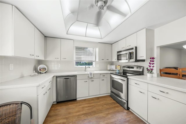 kitchen with sink, white cabinetry, stainless steel appliances, decorative backsplash, and light hardwood / wood-style flooring