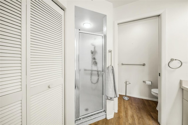 bathroom featuring vanity, a shower with shower door, hardwood / wood-style flooring, and toilet