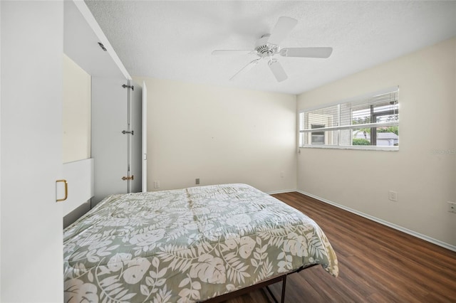 bedroom with ceiling fan, a textured ceiling, and dark hardwood / wood-style flooring