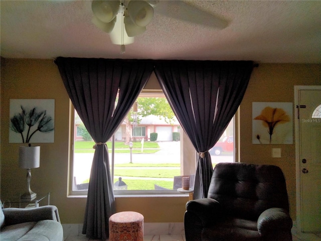 living room featuring ceiling fan, plenty of natural light, and a textured ceiling