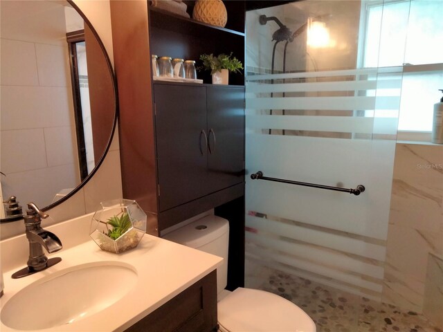 bathroom with tiled shower, vanity, and toilet