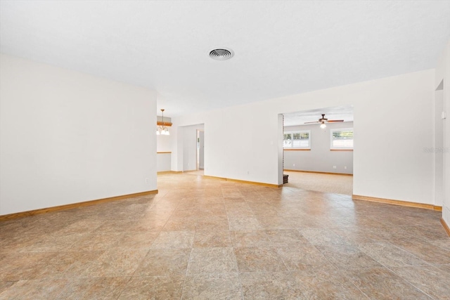 spare room with ceiling fan with notable chandelier