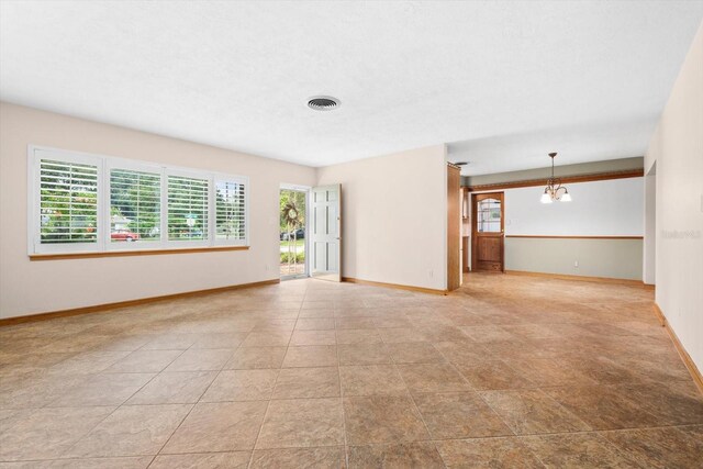 unfurnished living room featuring plenty of natural light and an inviting chandelier