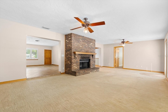 unfurnished living room featuring ceiling fan, a fireplace, light carpet, and a textured ceiling