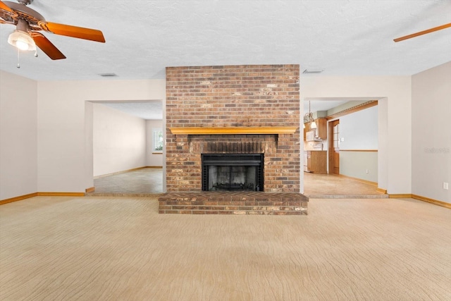 unfurnished living room featuring light colored carpet, a brick fireplace, ceiling fan, and a textured ceiling