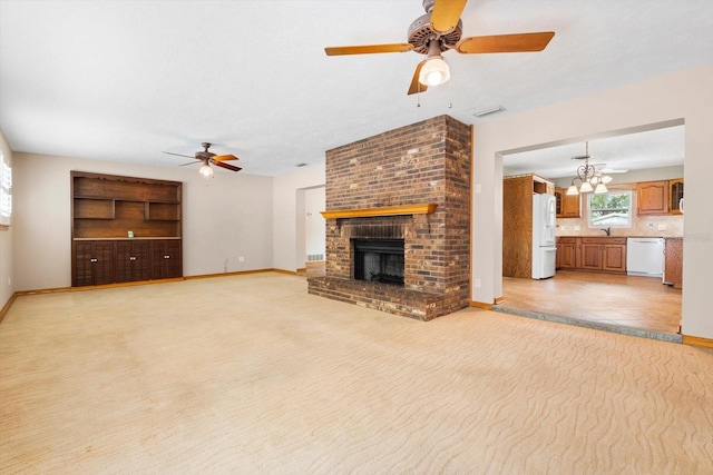 unfurnished living room featuring a brick fireplace, sink, and ceiling fan