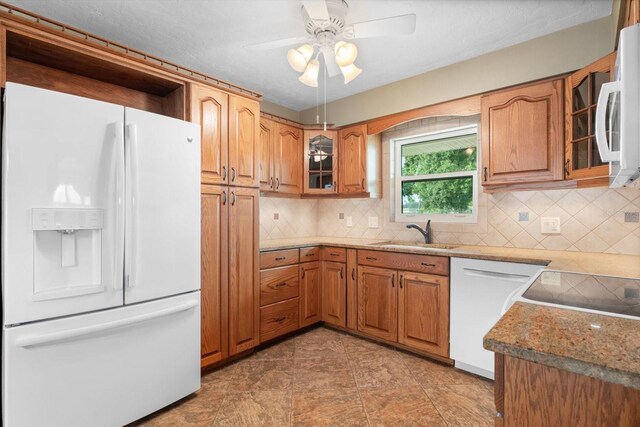 kitchen with white appliances, light stone countertops, sink, ceiling fan, and tasteful backsplash