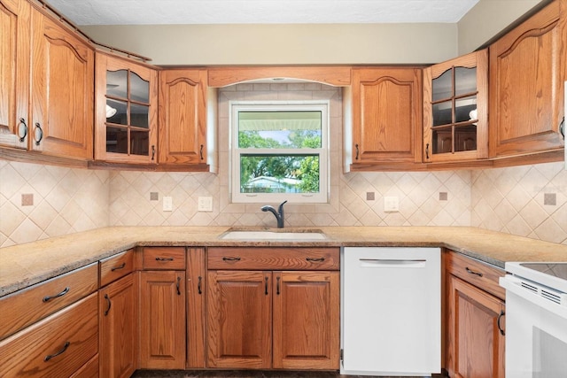 kitchen with dishwasher, sink, light stone countertops, and backsplash