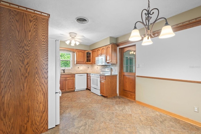 kitchen featuring ceiling fan with notable chandelier, white appliances, sink, decorative backsplash, and hanging light fixtures