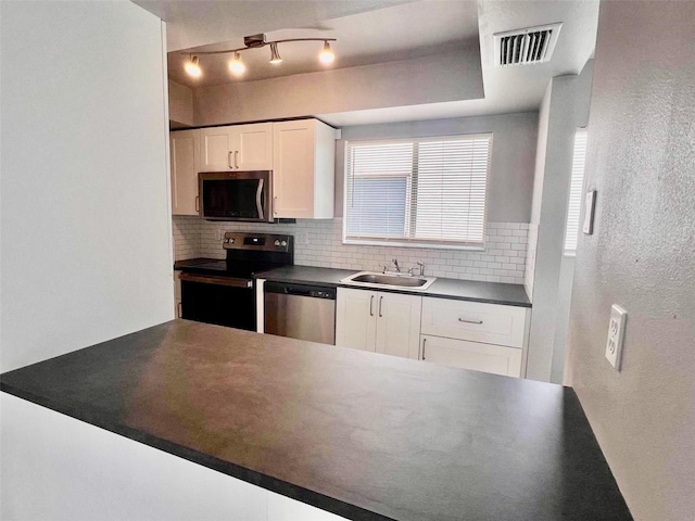 kitchen featuring appliances with stainless steel finishes, white cabinetry, backsplash, and sink