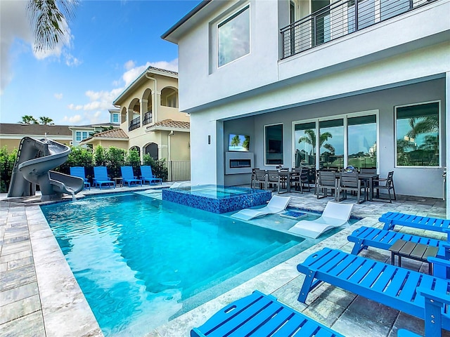 view of pool with a water slide and a patio