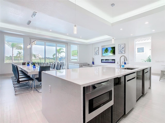 kitchen with pendant lighting, a wealth of natural light, a center island with sink, and sink