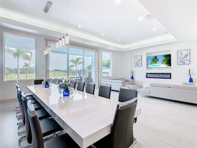 dining space featuring a raised ceiling, plenty of natural light, and an inviting chandelier