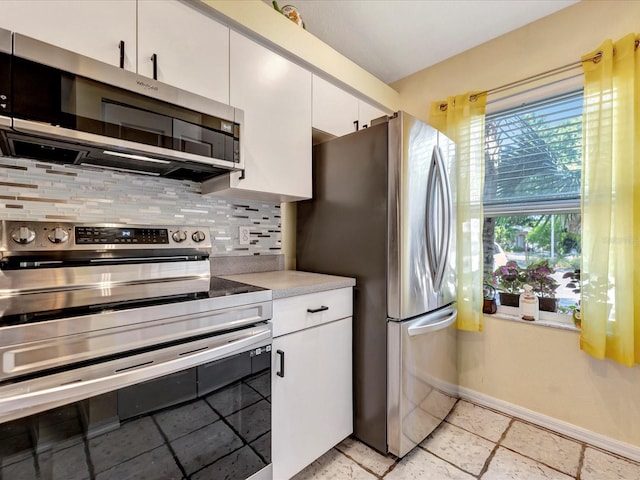 kitchen with appliances with stainless steel finishes, white cabinets, and backsplash