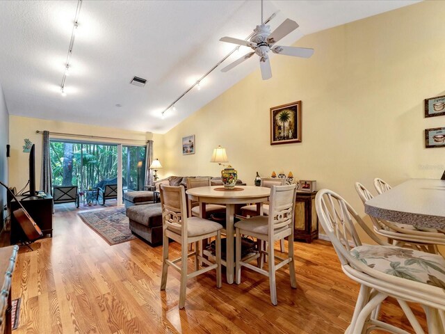 dining room with ceiling fan, lofted ceiling, track lighting, and light wood-type flooring