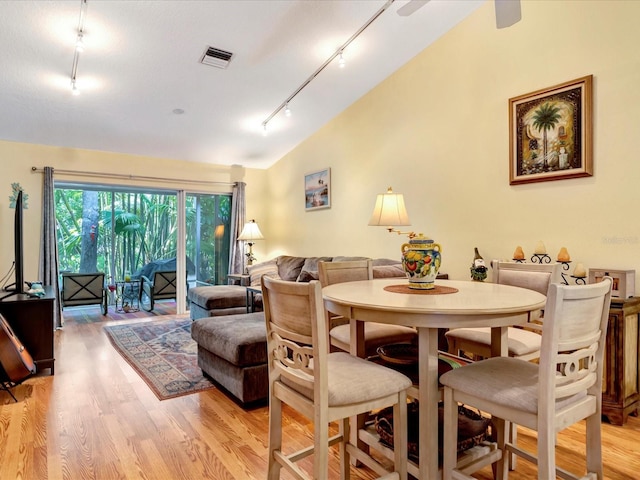 dining room with lofted ceiling, rail lighting, and light wood-type flooring