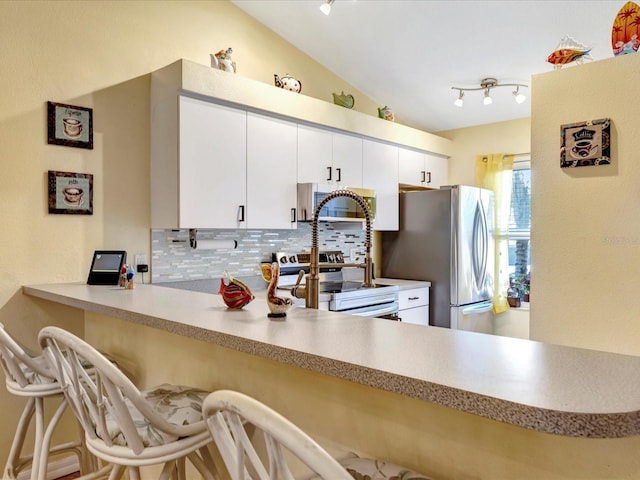 kitchen with stainless steel refrigerator, backsplash, range with electric stovetop, white cabinets, and kitchen peninsula