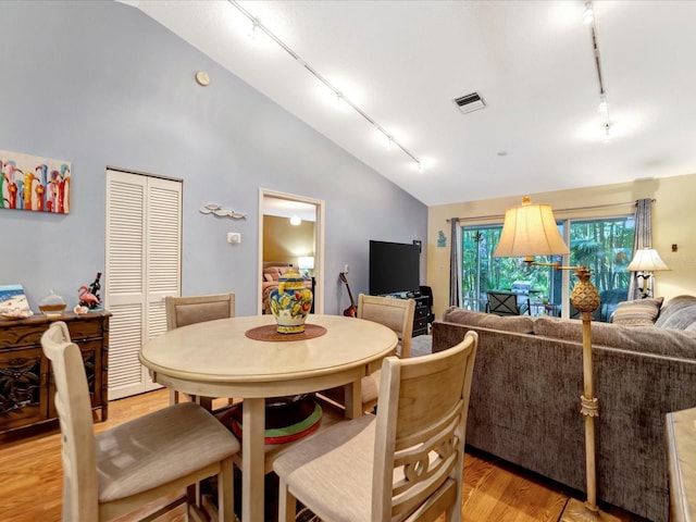 dining area featuring vaulted ceiling, rail lighting, and light wood-type flooring