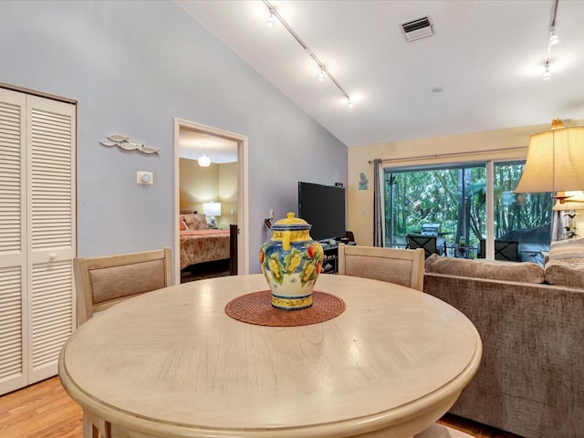 dining space with vaulted ceiling, rail lighting, and light wood-type flooring