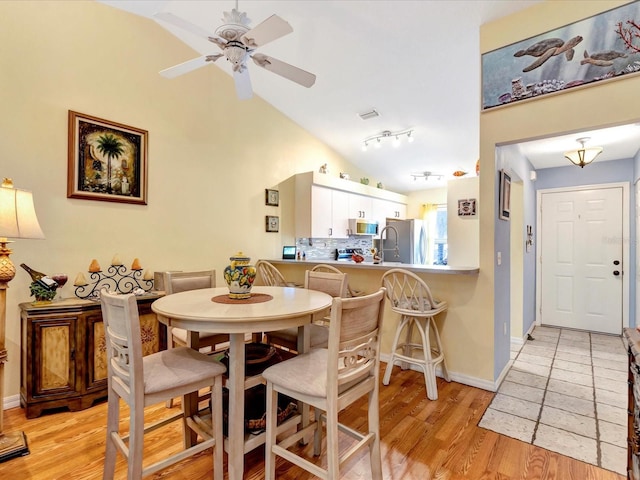 dining space featuring lofted ceiling, ceiling fan, and light hardwood / wood-style flooring