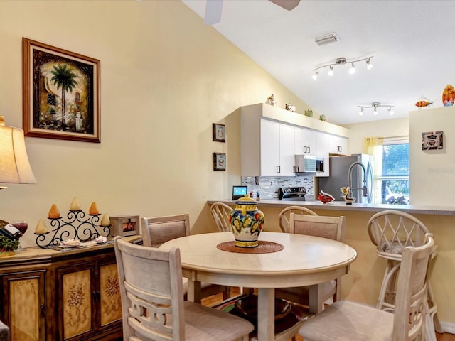 dining area featuring track lighting and lofted ceiling