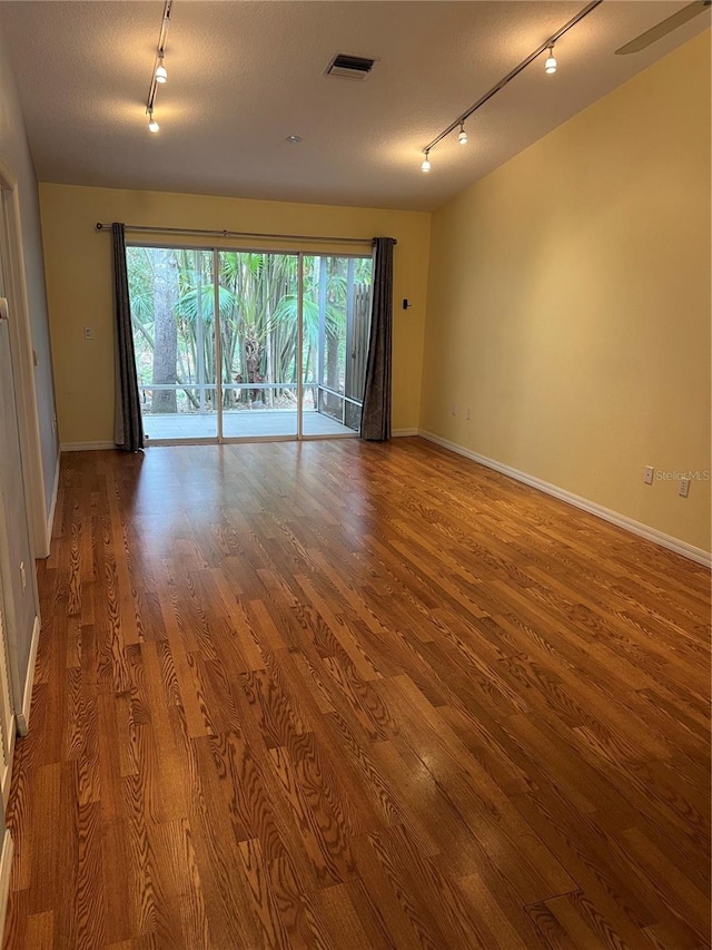 unfurnished room with track lighting, wood-type flooring, and a textured ceiling