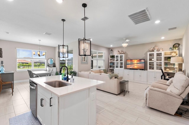 kitchen with sink, decorative light fixtures, a kitchen island with sink, white cabinetry, and ceiling fan with notable chandelier