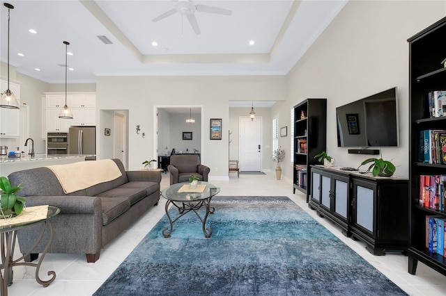 living room featuring light tile patterned floors, a raised ceiling, ceiling fan, and sink