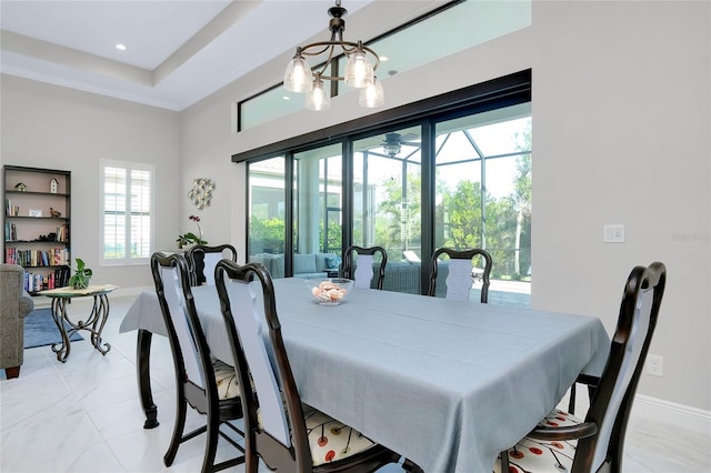 dining space with baseboards, a sunroom, an inviting chandelier, a tray ceiling, and recessed lighting