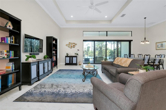 tiled living room with ceiling fan with notable chandelier, crown molding, and a tray ceiling