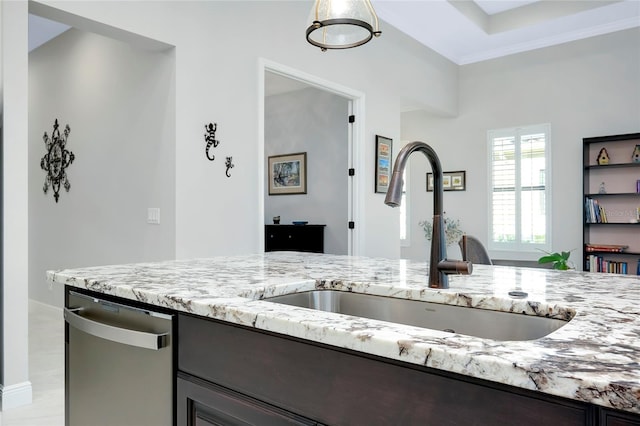 kitchen featuring stainless steel dishwasher, light stone counters, and a sink