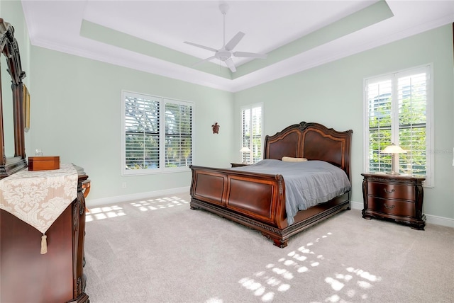 bedroom with ceiling fan, light colored carpet, crown molding, and a tray ceiling