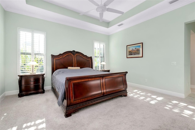 bedroom featuring light carpet, a ceiling fan, visible vents, baseboards, and a raised ceiling