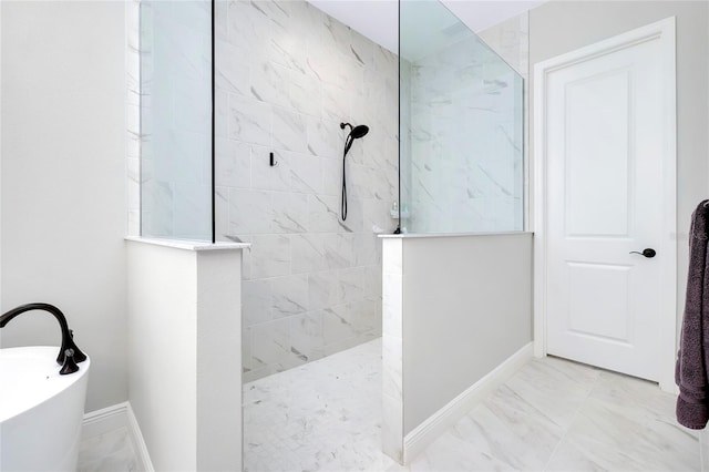 bathroom with a walk in shower, marble finish floor, a freestanding tub, and baseboards