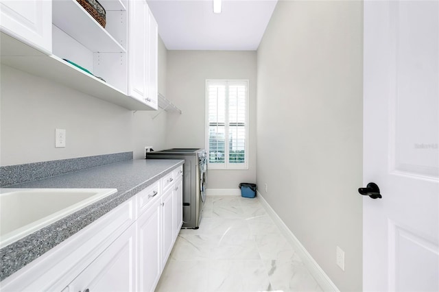 laundry room featuring cabinet space, baseboards, washer and clothes dryer, marble finish floor, and a sink