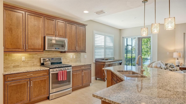 kitchen with light tile patterned flooring, sink, hanging light fixtures, stainless steel appliances, and backsplash