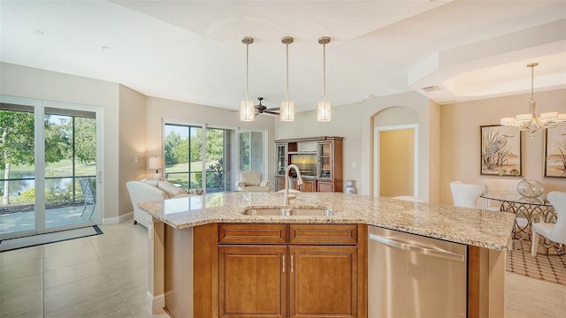 kitchen with dishwasher, sink, a notable chandelier, an island with sink, and light stone countertops